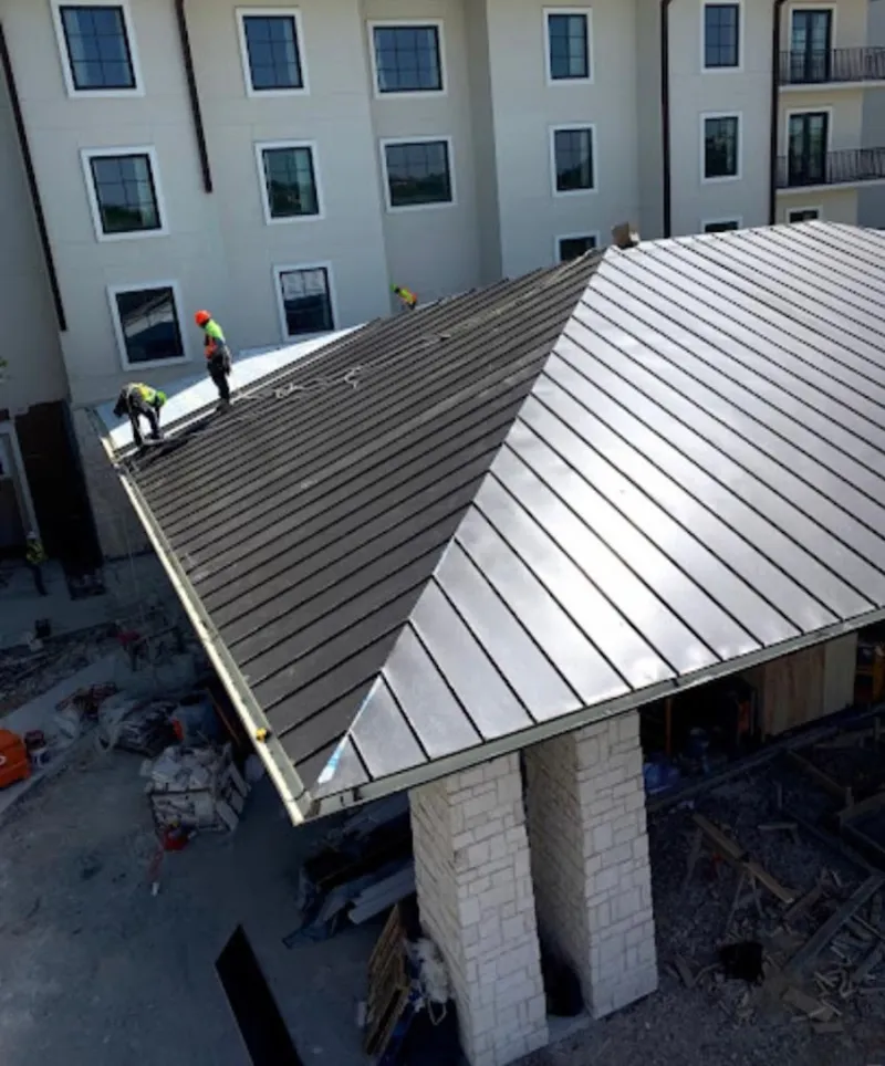 Crew installing standing seam metal roof panels on a commercial project in Antelope